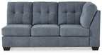 Denim-blue upholstered sofa with tufted back, three front seat cushions, rounded arm, legs