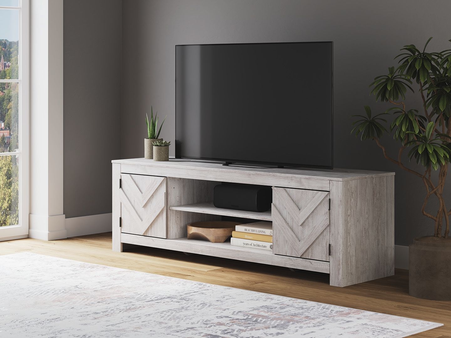 Light gray TV stand with chevron doors and open shelves for media