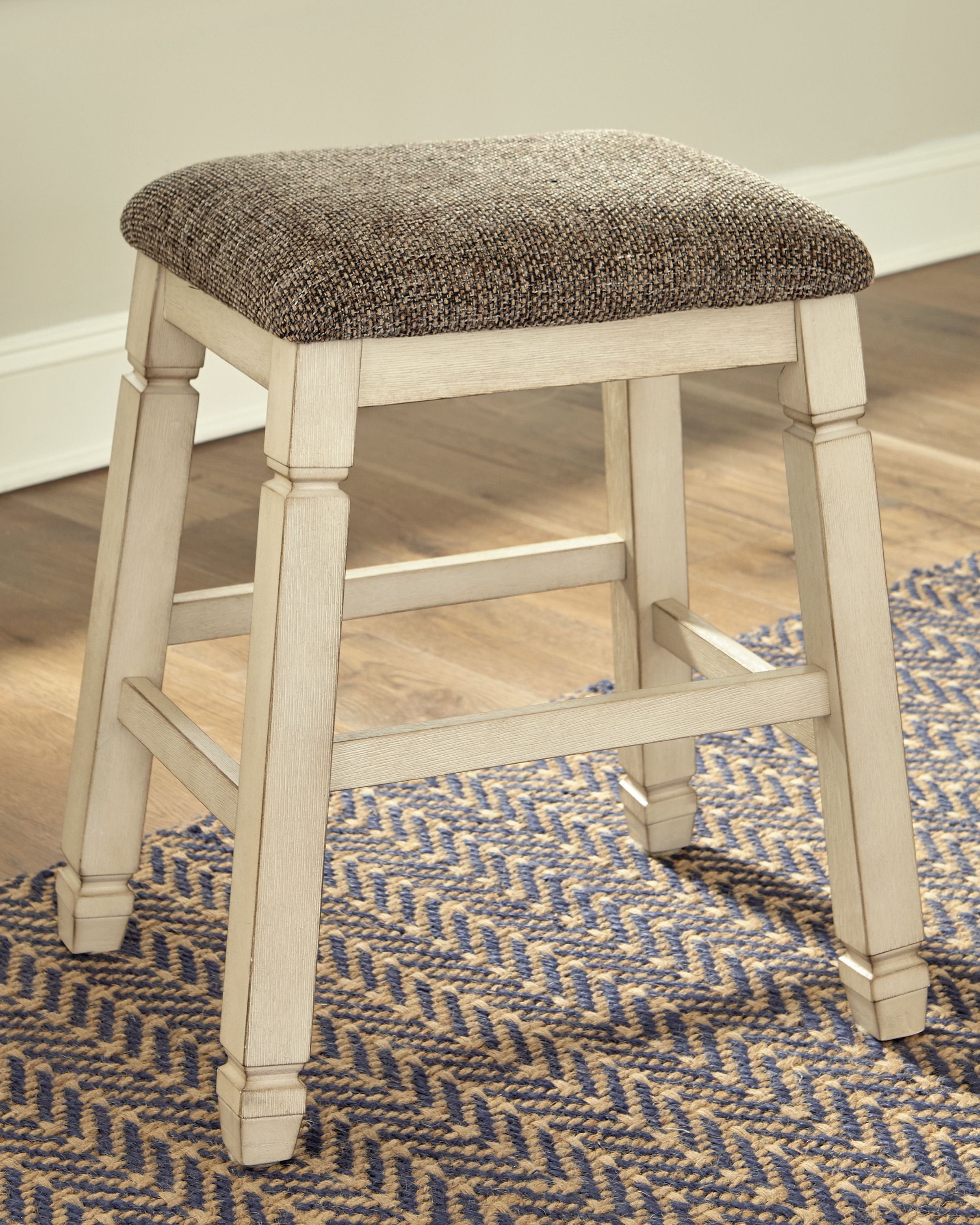 Upholstered stool with textured neutral fabric seat and light wood turned legs, open frame