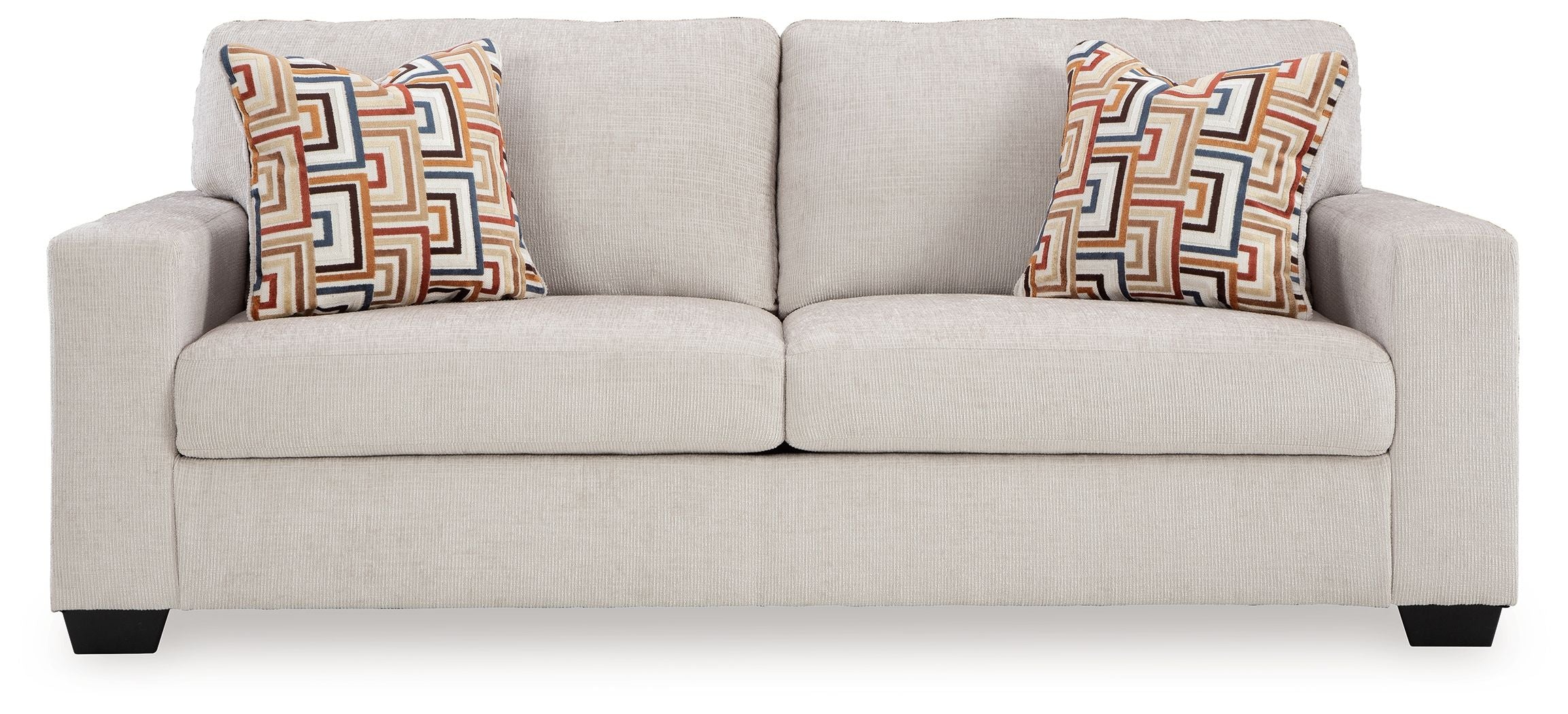 Sofa sleeper with light beige upholstery, two geometric throw pillows, and black legs.