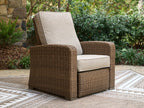 Beige cushioned wicker recliner chair with curved back and wide arms