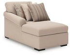 Beige corner chaise with black legs and three throw pillows, striped and patterned