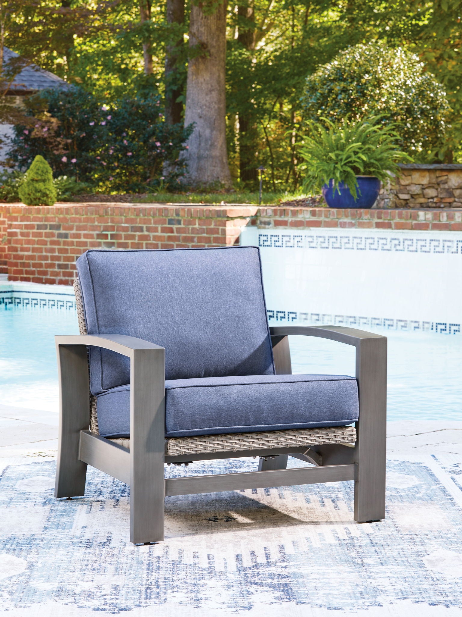 Blue lounge chair with gray frame, cushioned seat and backrest, woven base panel