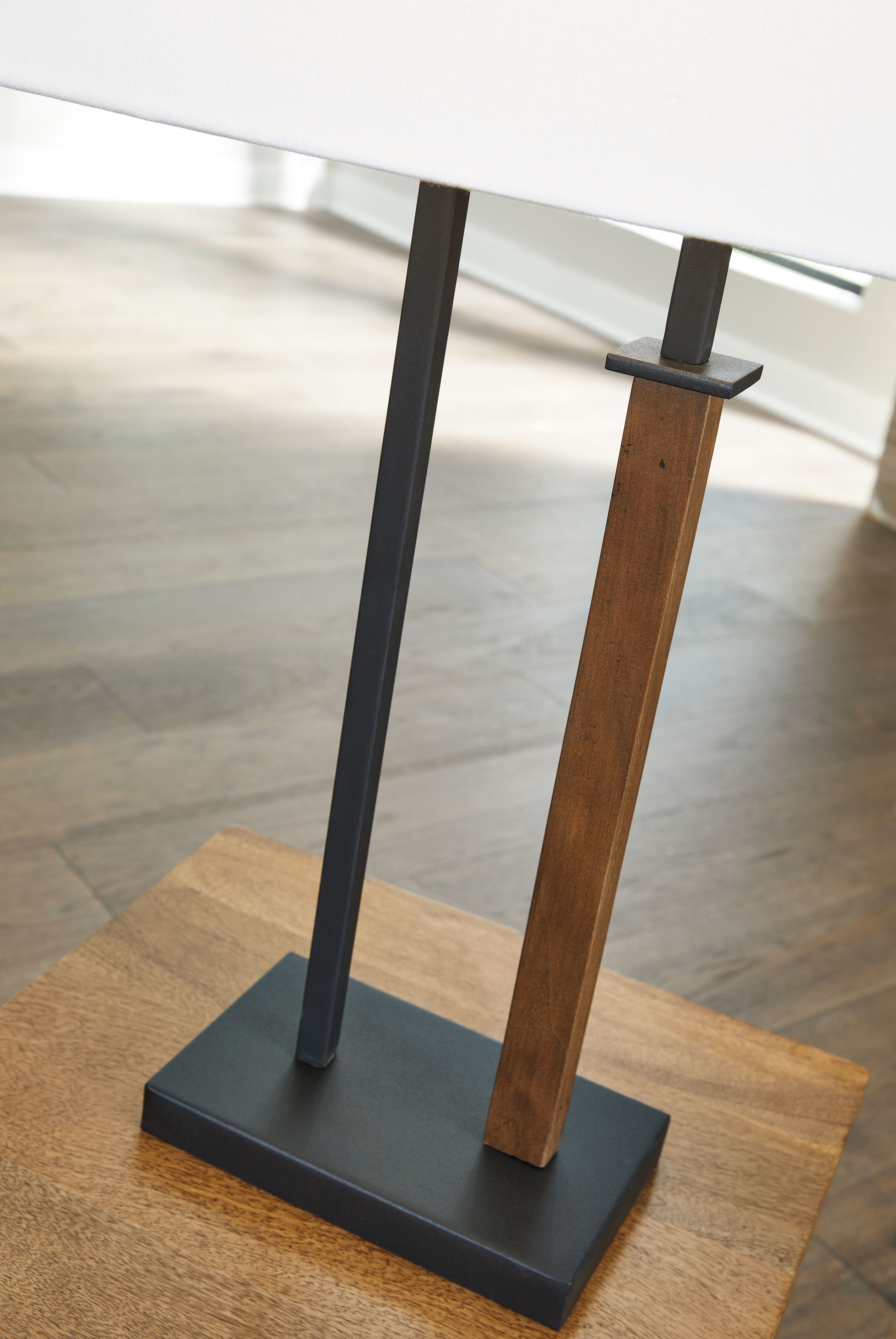 Metal table lamp with black metal base, brown wood column, and white shade, side view
