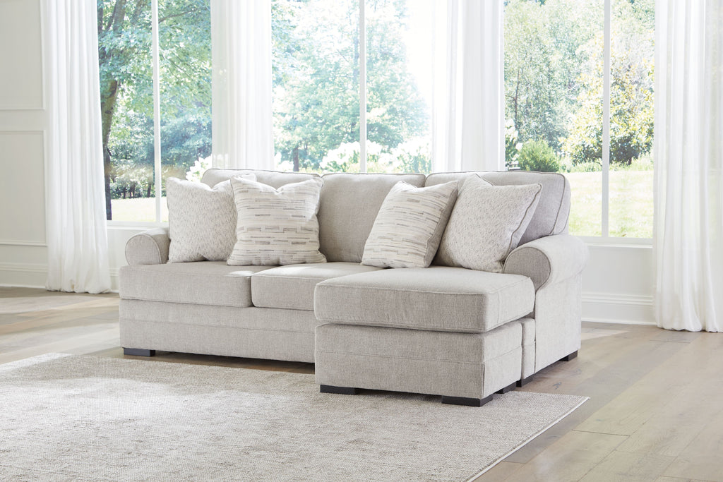 Light gray sofa chaise with layered back cushions and patterned throw pillows