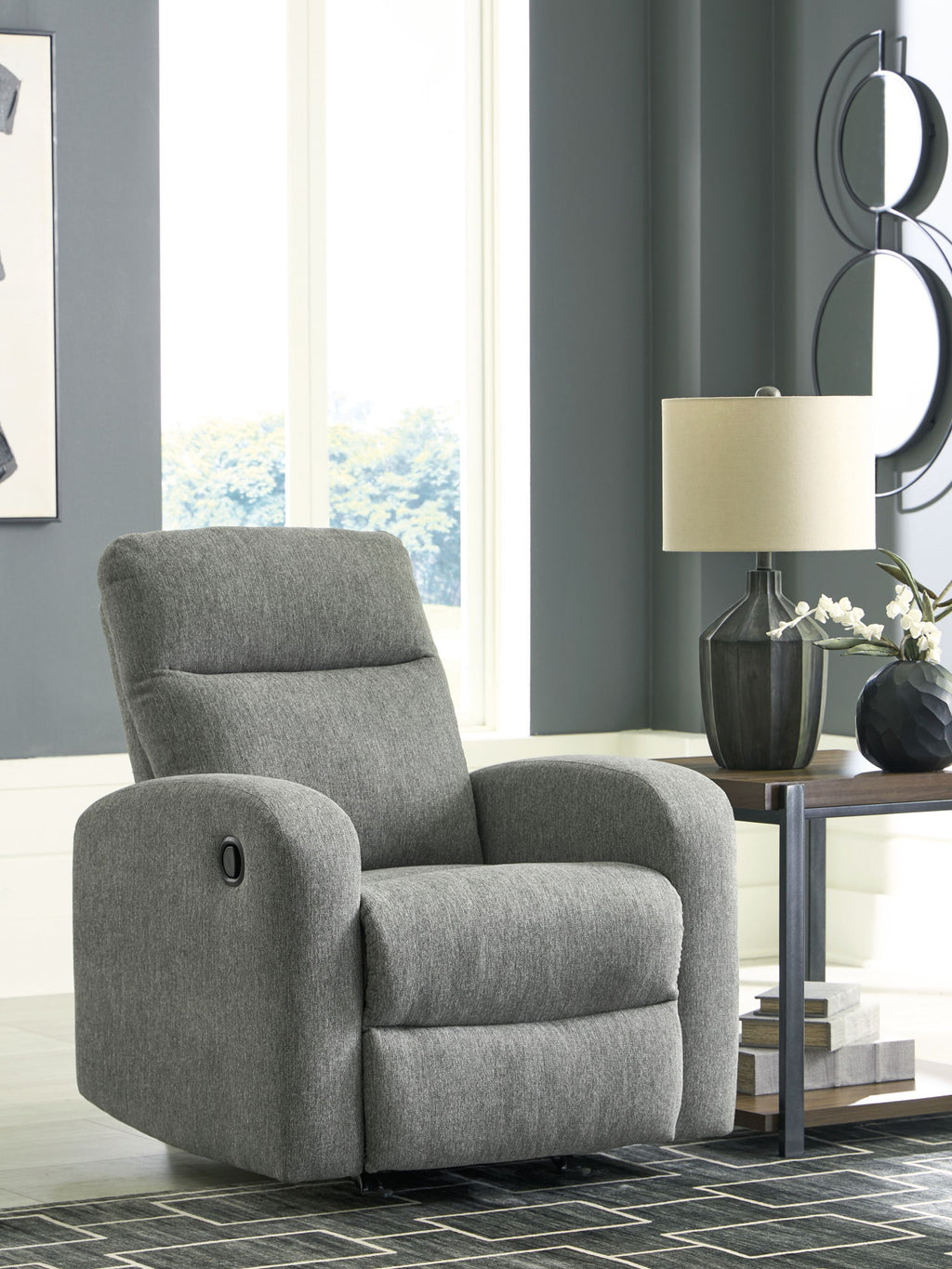 Gray fabric rocker recliner with padded headrest, armrests, and circular control