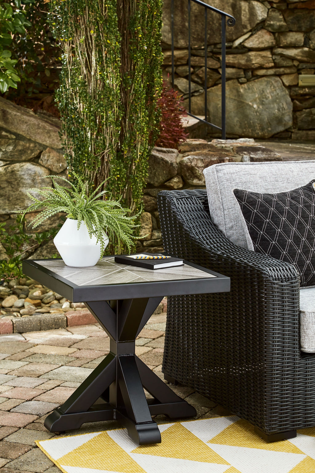 Outdoor black square end table with X-style base near seating