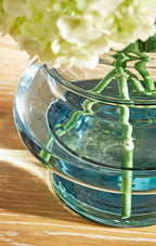 Blue glass vase with green stems and white flowers, side view
