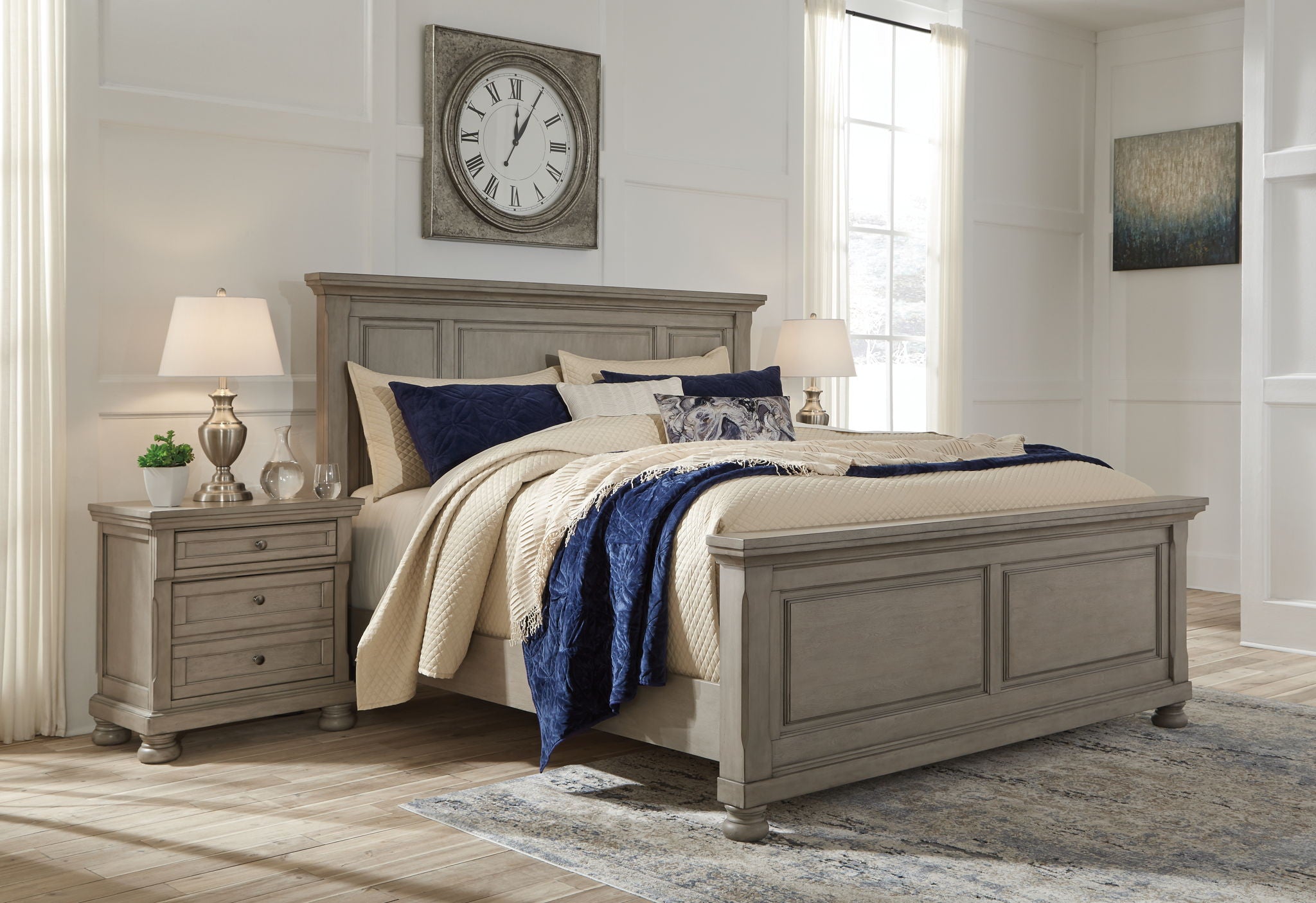 Gray panel bed with cream quilt, navy throw, and layered patterned pillows