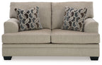 Light beige fabric loveseat with two geometric patterned pillows, head-on view