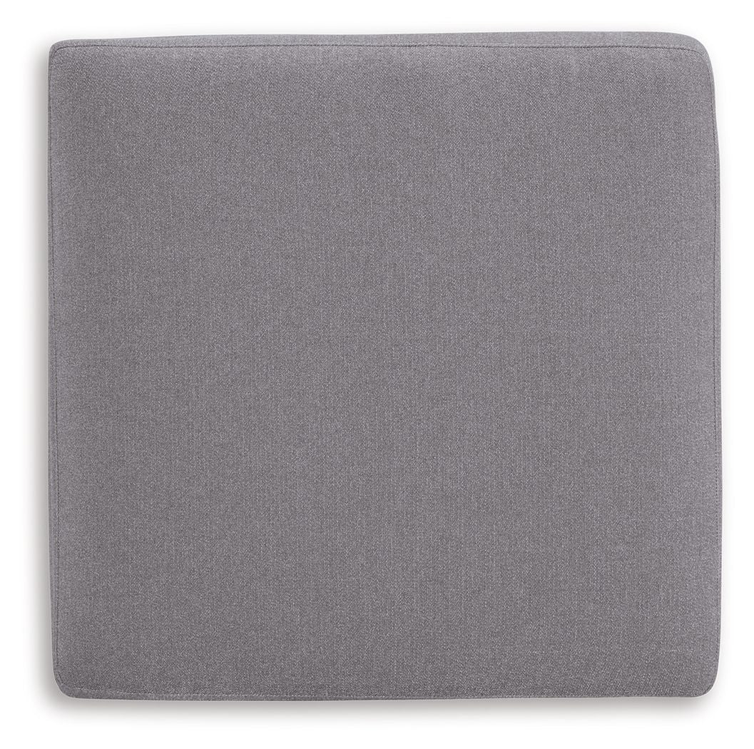 Gray fabric accent ottoman with square back panel and rounded top cushion.