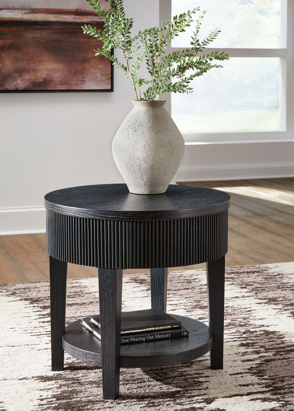 Black round end table with ribbed skirt, round top, and storage shelf