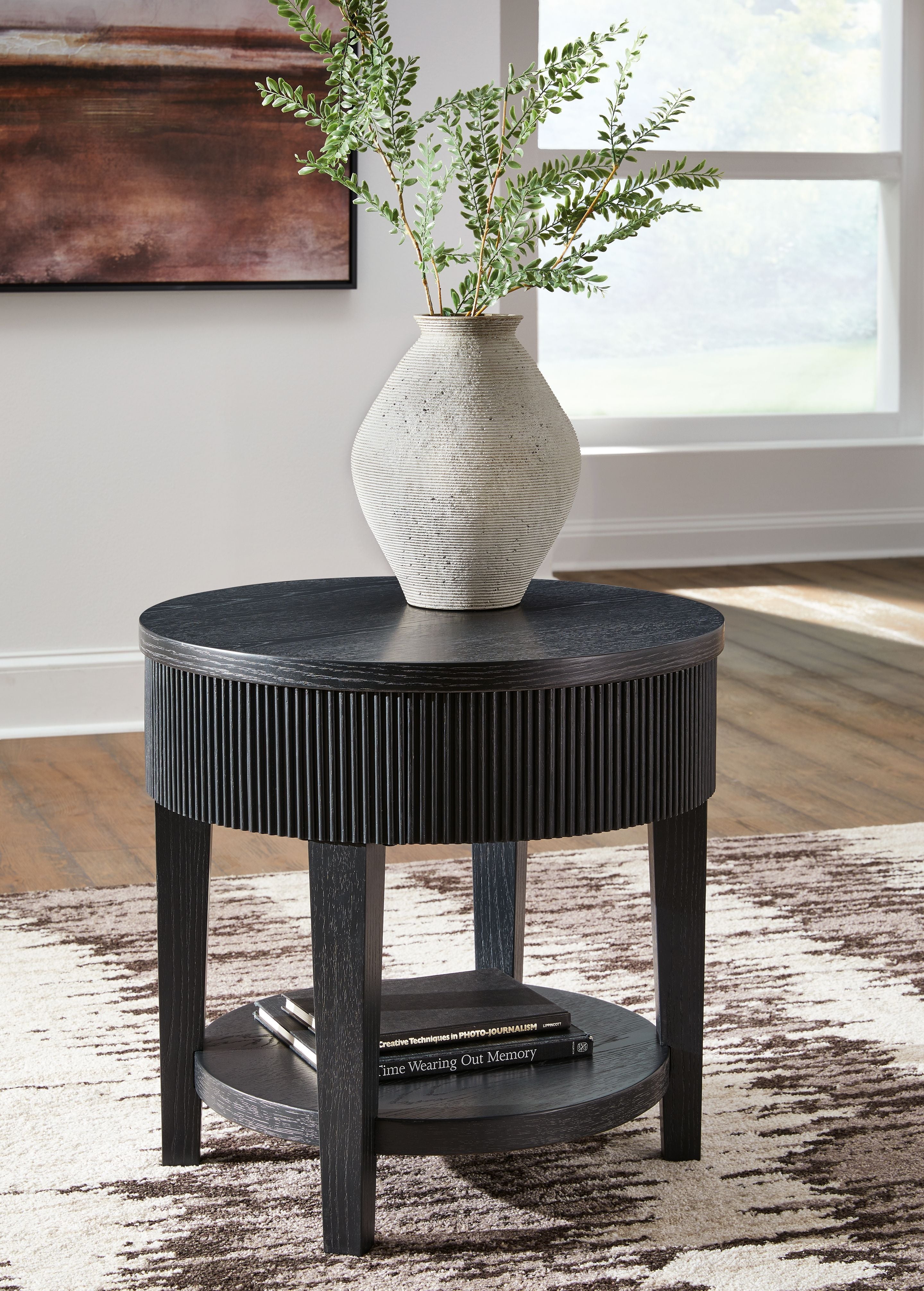 Black round end table with ribbed skirt, round top, and storage shelf