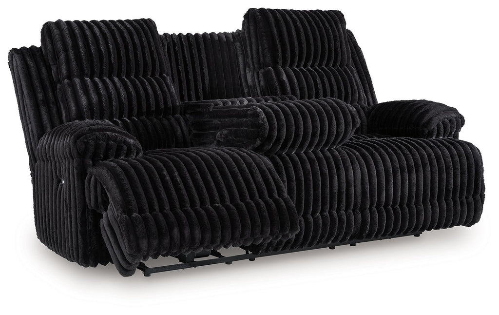 Black corduroy reclining sofa with extended footrest and thick, ribbed cushions