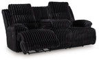 Black corduroy reclining sofa with extended footrest and thick, ribbed cushions