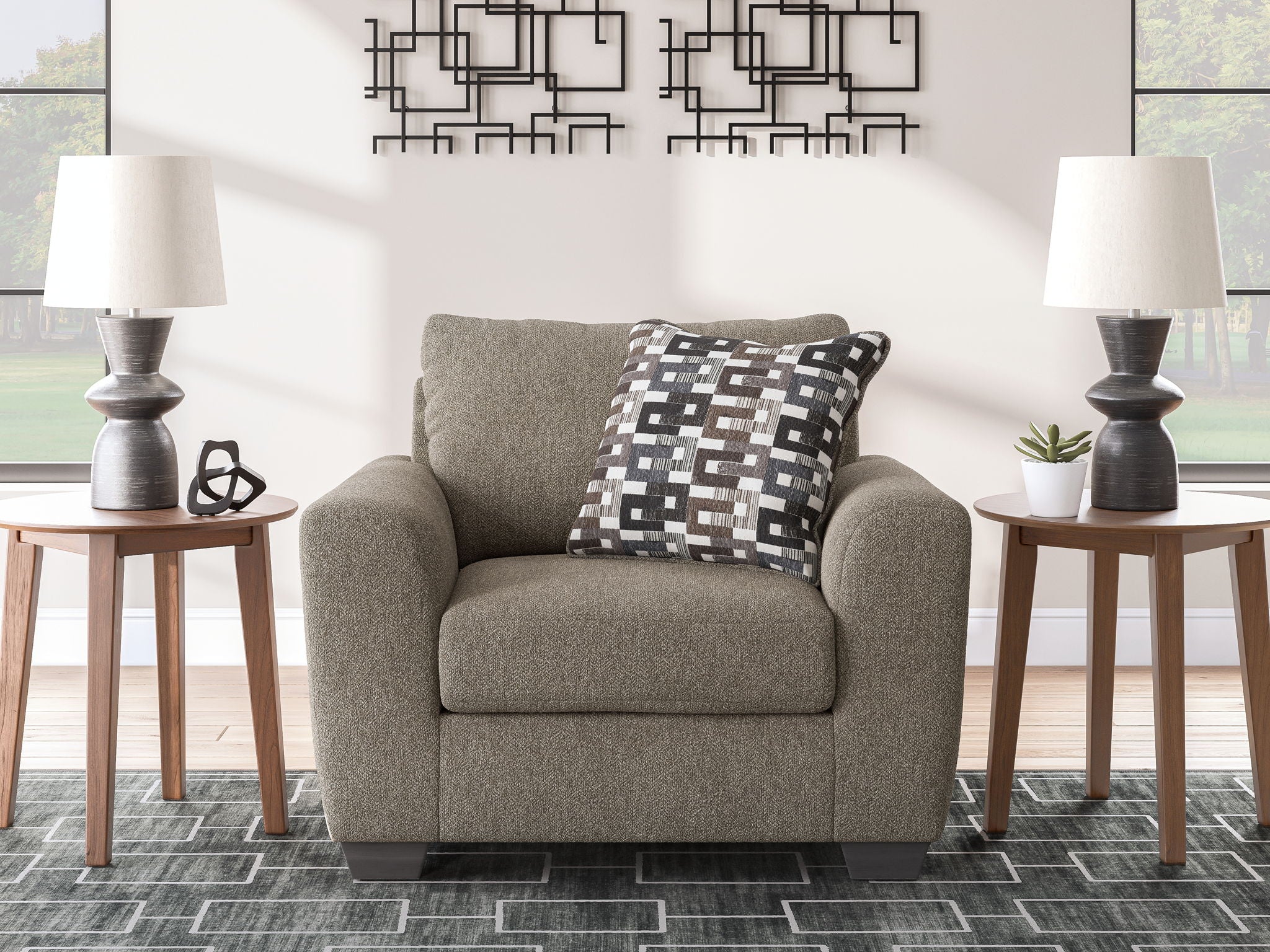 Upholstered chair and a half with dark gray upholstery and geometric patterned cushion