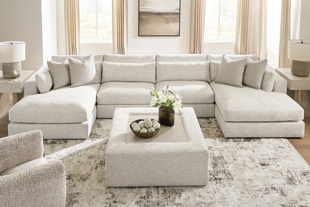 Beige sectional sofa with corner chaise section, throw pillows, and tufted seat cushions