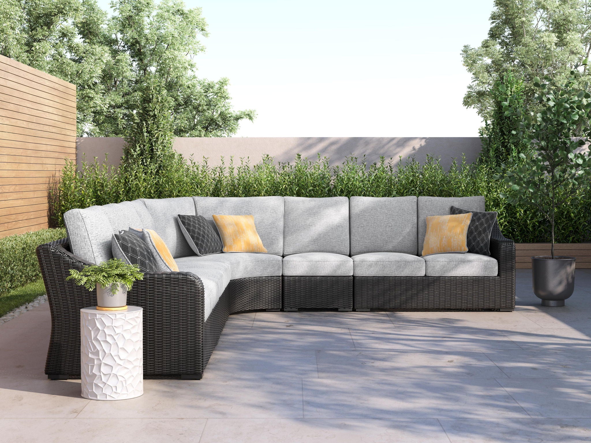 L-shaped outdoor sectional sofa with gray cushions, black armrests, yellow pillows