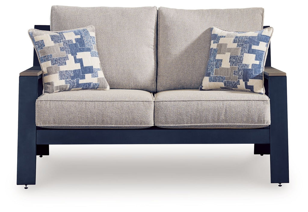 Gray upholstered loveseat with two blue patterned throw pillows and dark frame