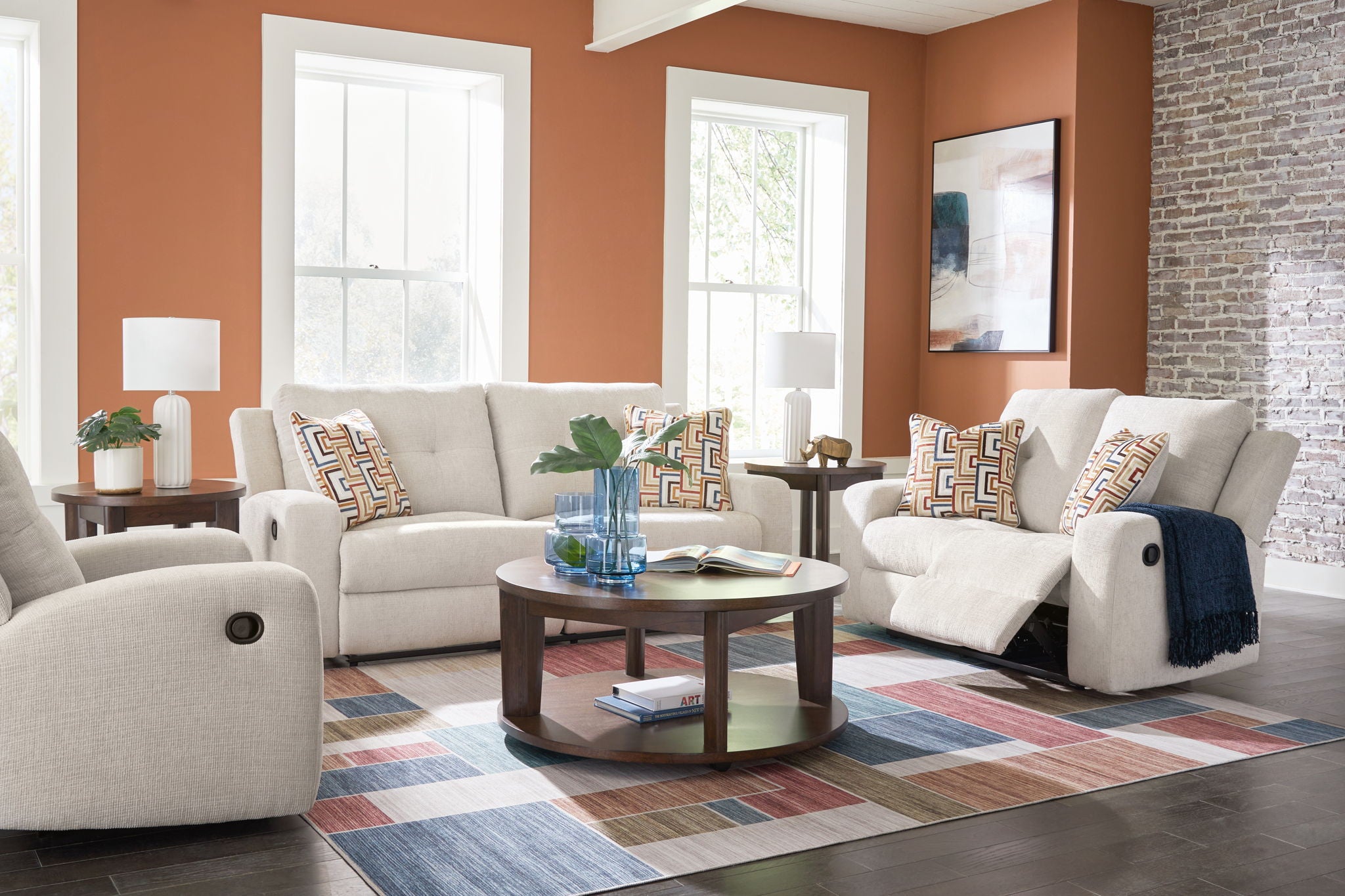 Beige reclining sofa and loveseat set with patterned throw pillows