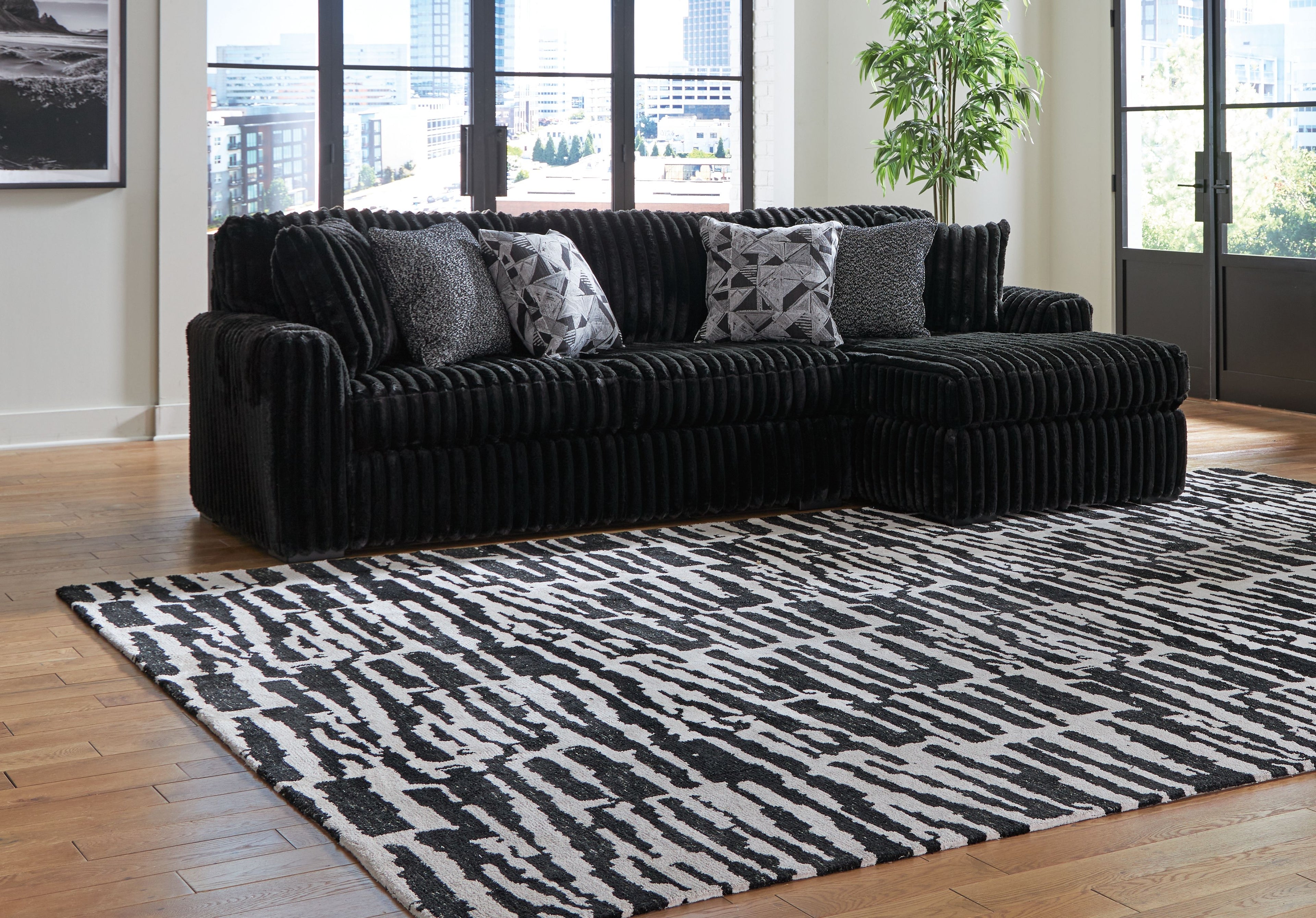 Black corduroy sectional sofa with chaise arm and tufted seat cushions