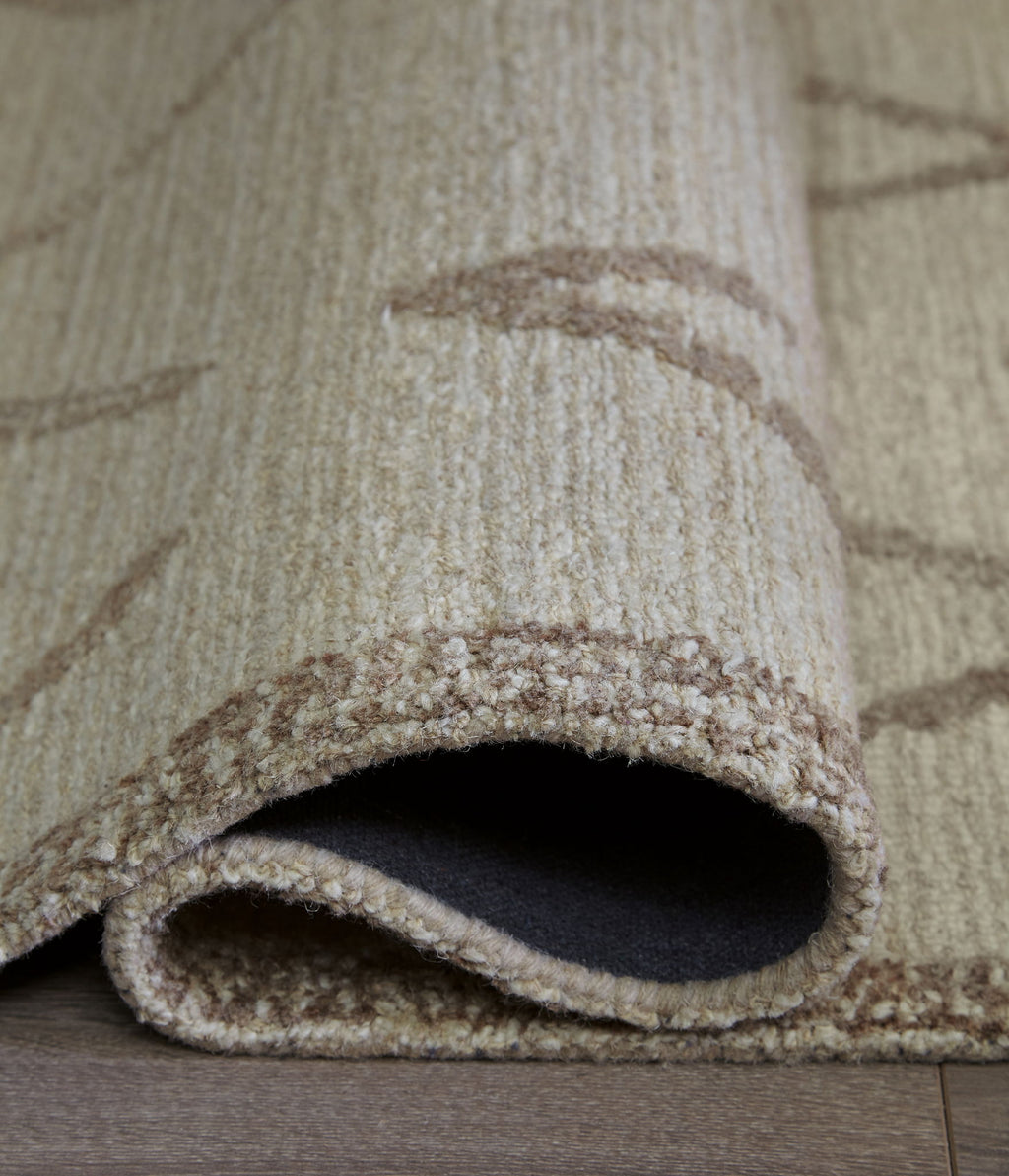 Beige area rug edge detail with brown border and visible dark underside.