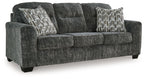 Dark gray fabric sofa with two patterned accent pillows and wide arms