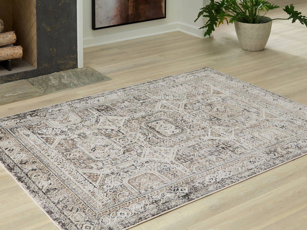 Distressed geometric area rug with light off-white base and gray motifs on floor