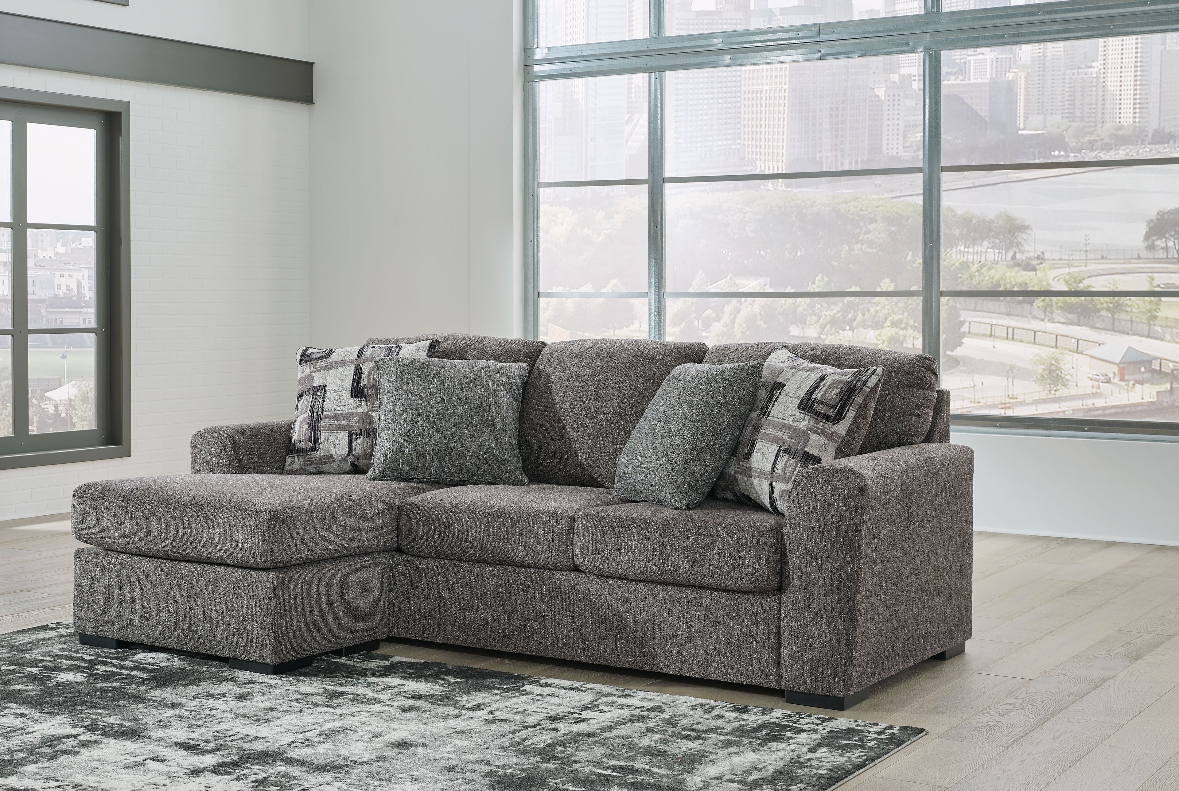 Pewter fabric sofa chaise with chaise section, three back pillows and two patterned throws