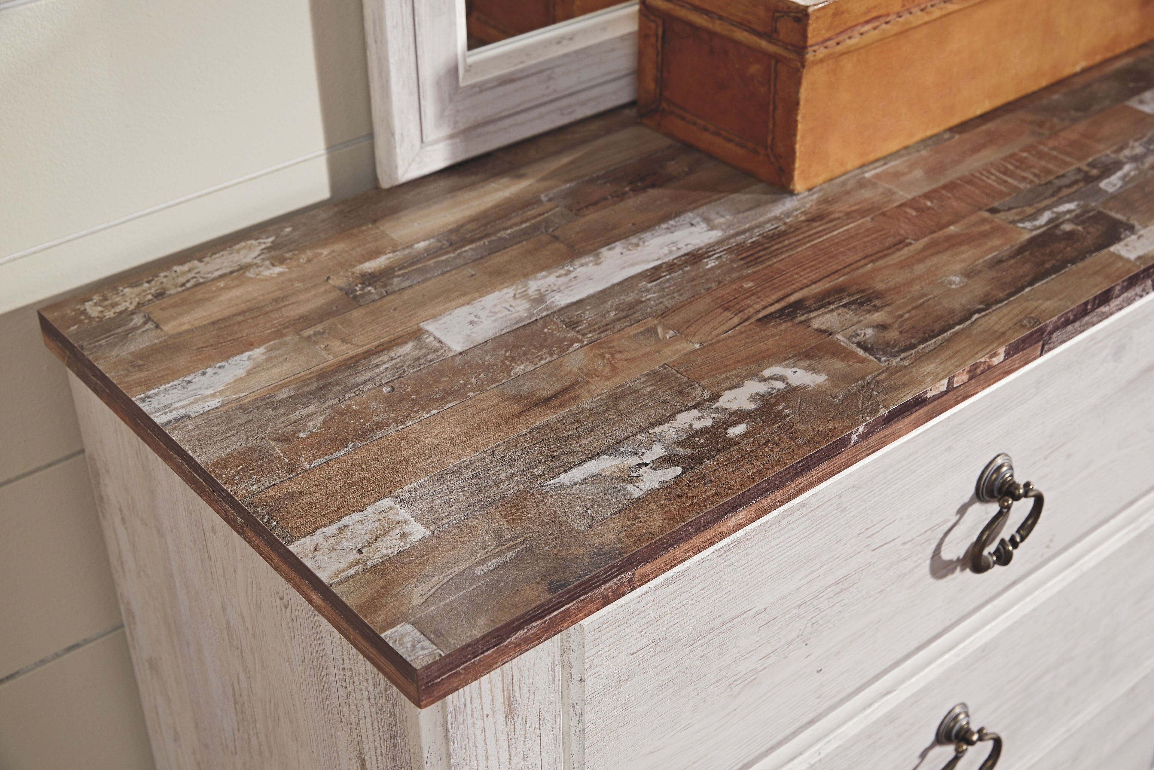 Five-drawer chest close-up with distressed wood top and dark metal knob pulls