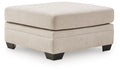 Beige upholstered ottoman with square cushioned top and dark wood legs