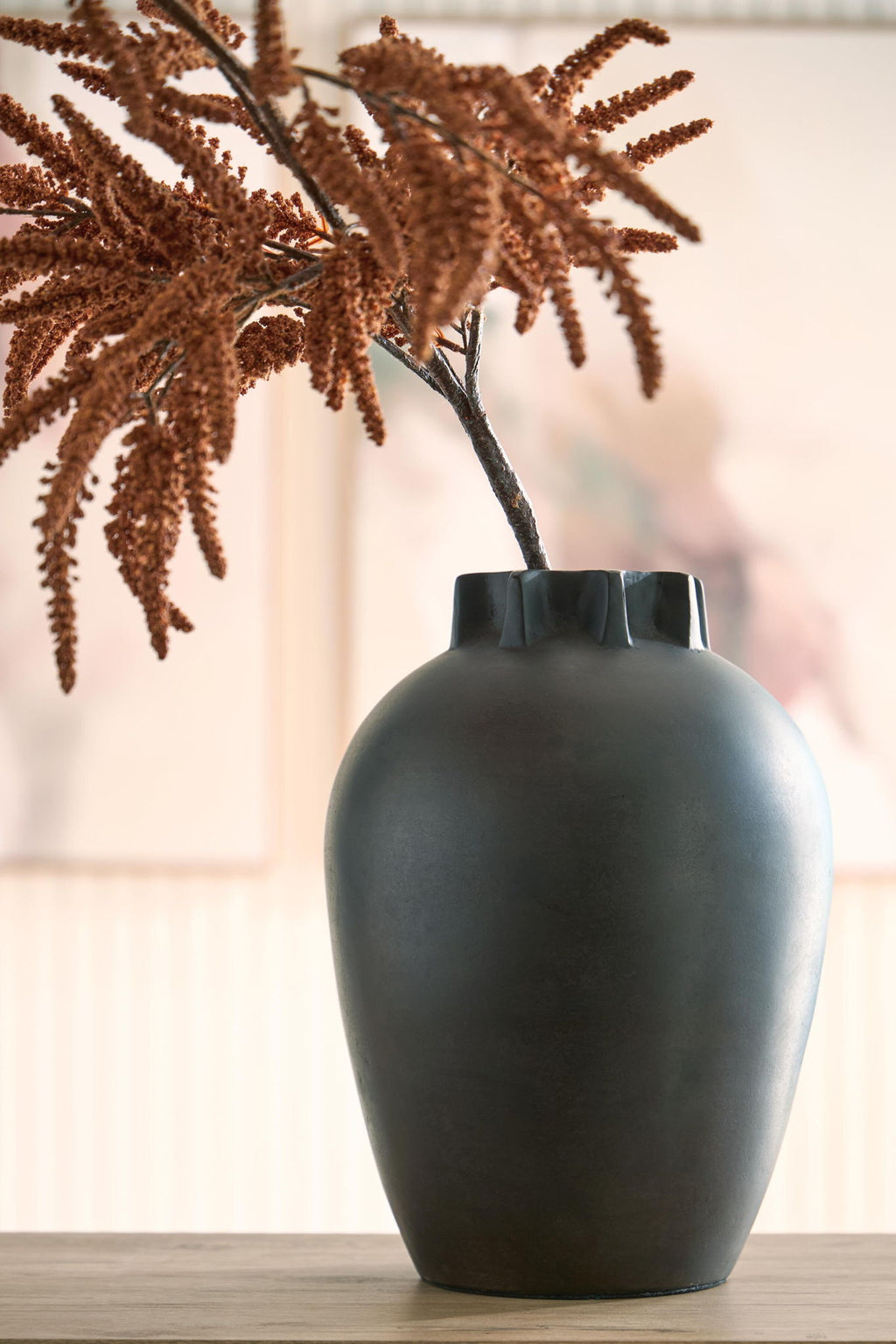 Antique black ceramic vase on table with decorative dried branch stems
