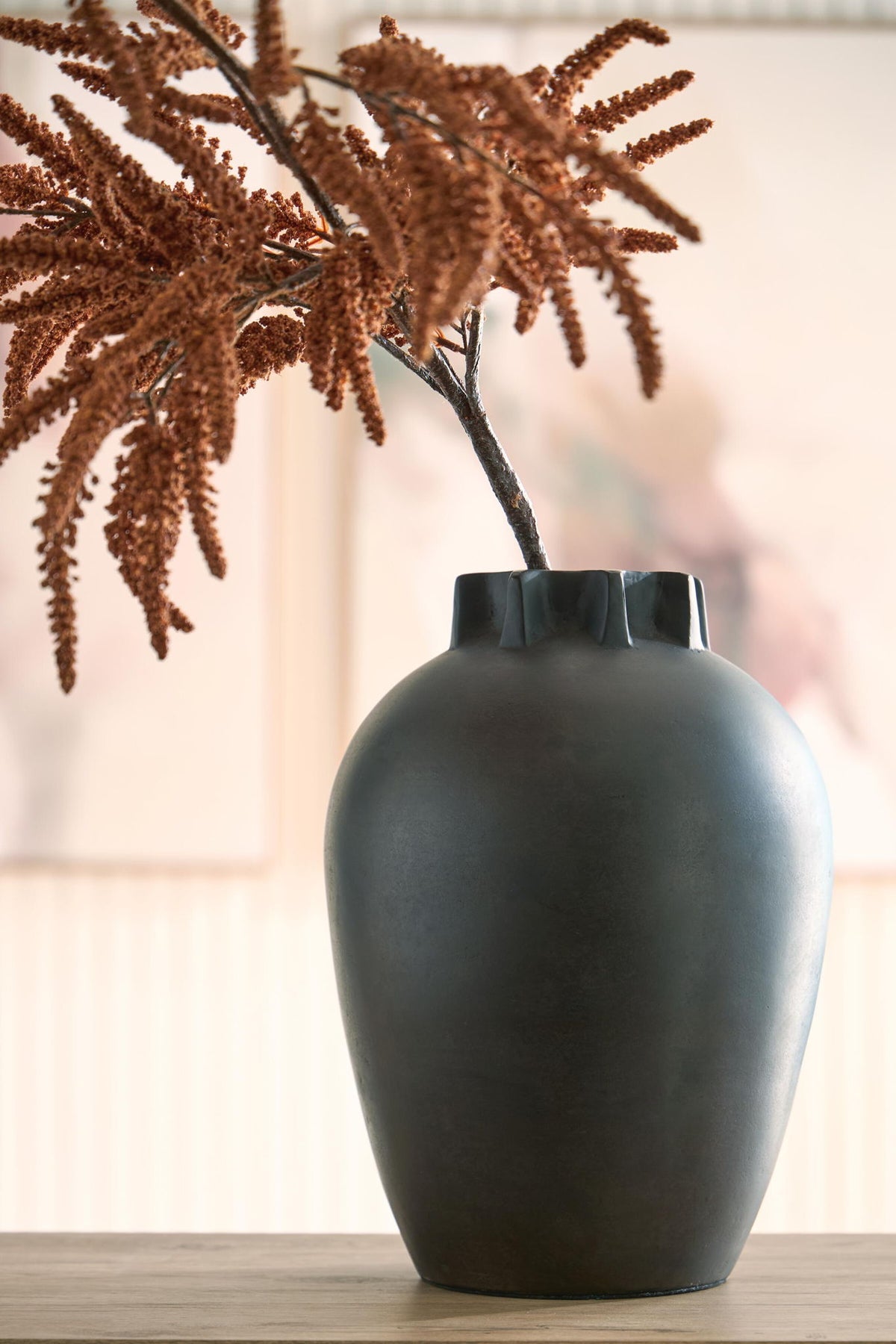 Antique black ceramic vase on table with decorative dried branch stems