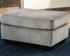 Light gray upholstered ottoman with cushioned top and squared body