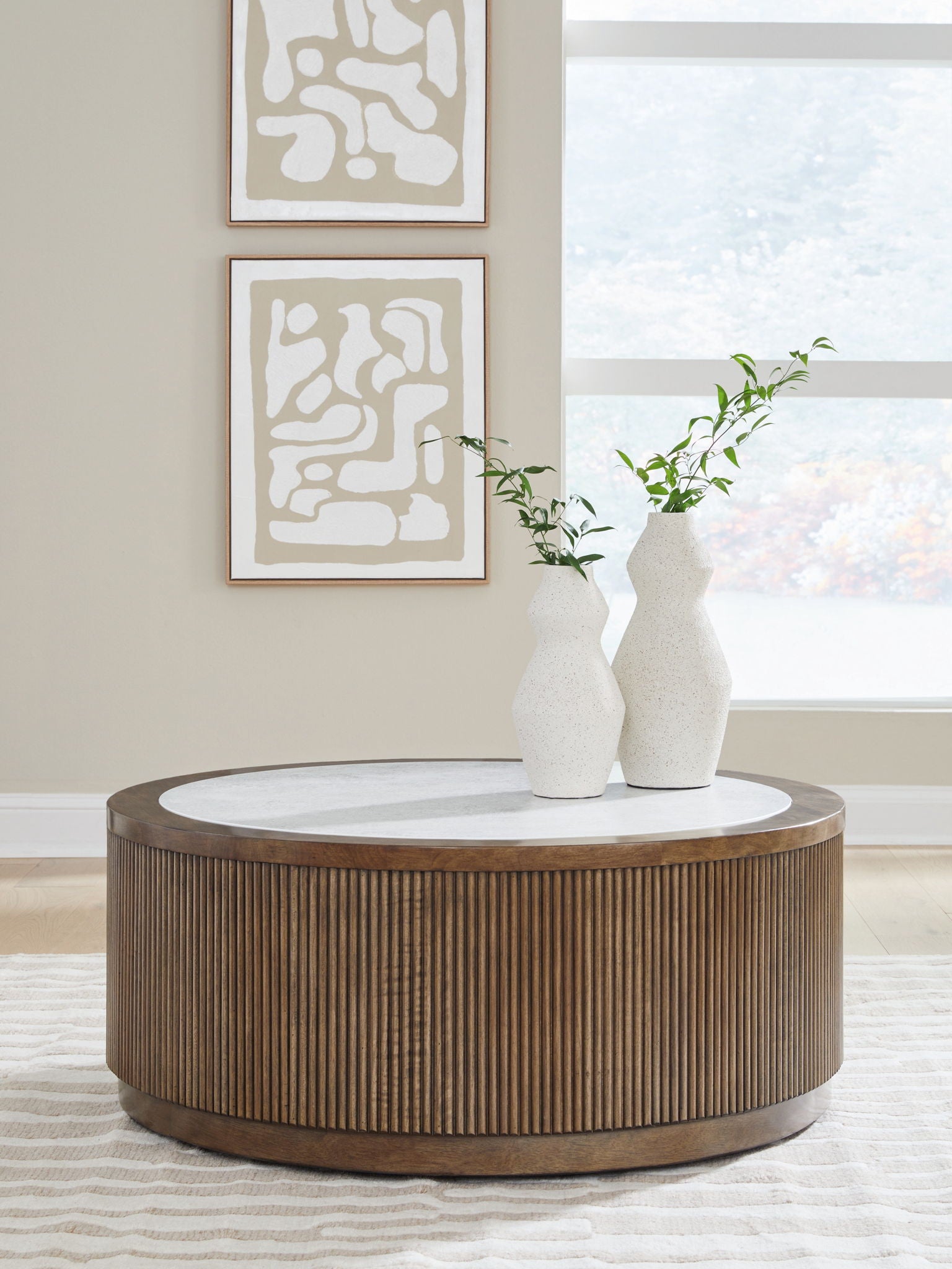 Round side table with slatted wood sides and gray round top, with a white vase.