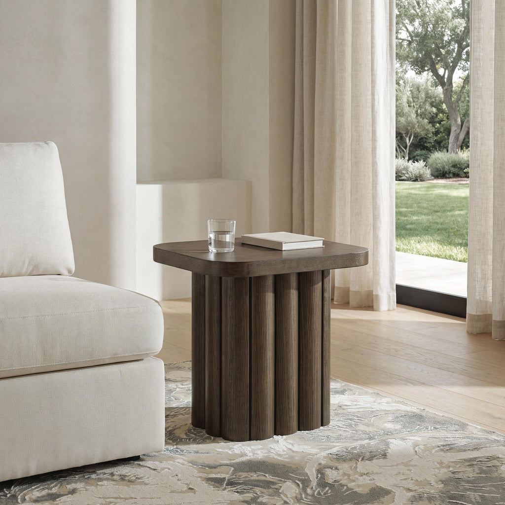 Dark brown side table with oval top and ribbed base next to sofa in living room