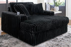 Oversized chaise with ribbed black fabric upholstery and wide track-style seat.