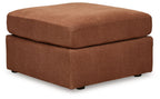 Light brown accent ottoman with cushioned top and two-tier square base, black feet.