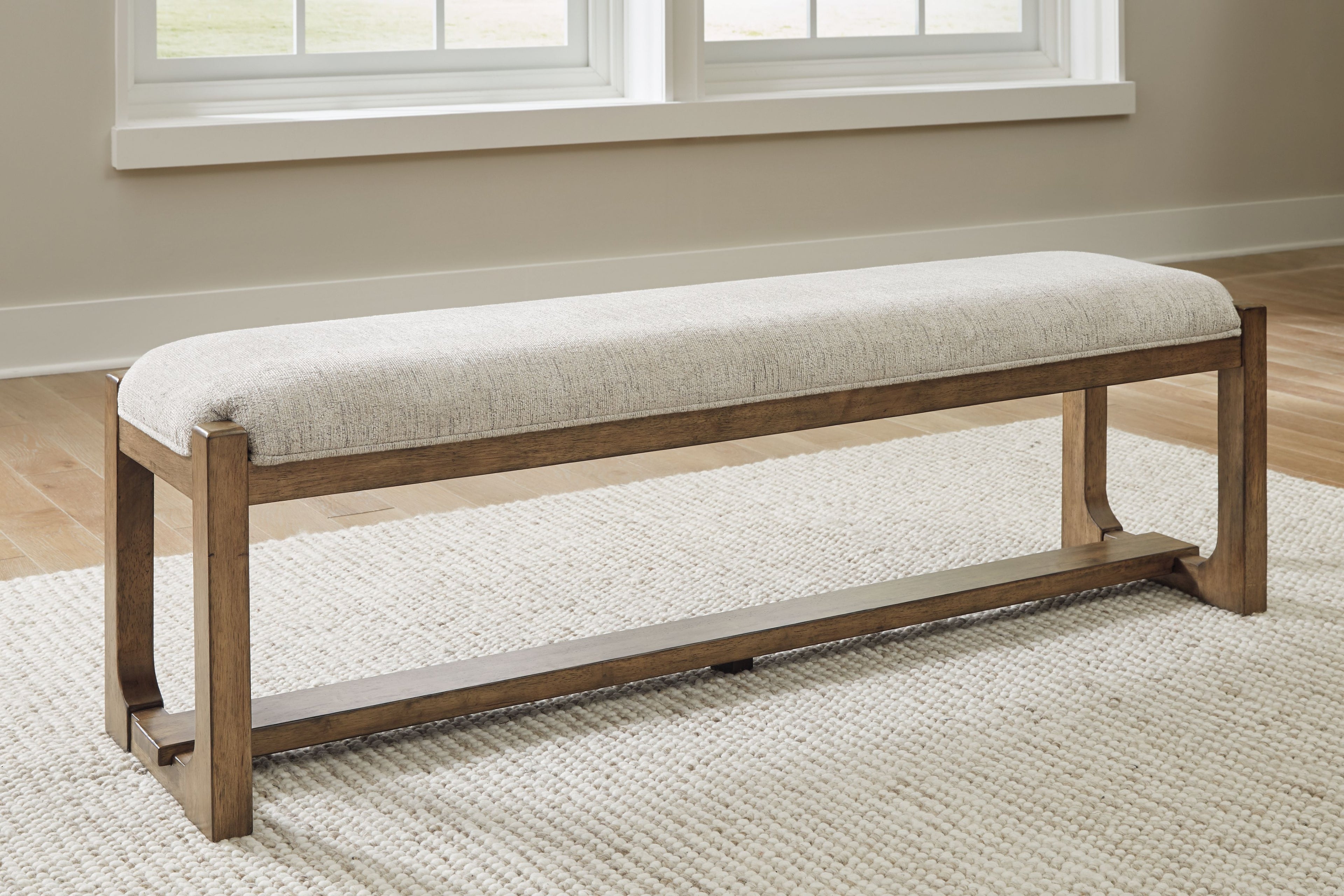 Upholstered dining bench, oatmeal seat with light brown frame and low shelf, angled view
