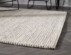 Beige woven rug with low loop pile and stitched border, corner view