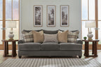 Gray upholstered sofa with tufted arms and plaid and tan throw pillows