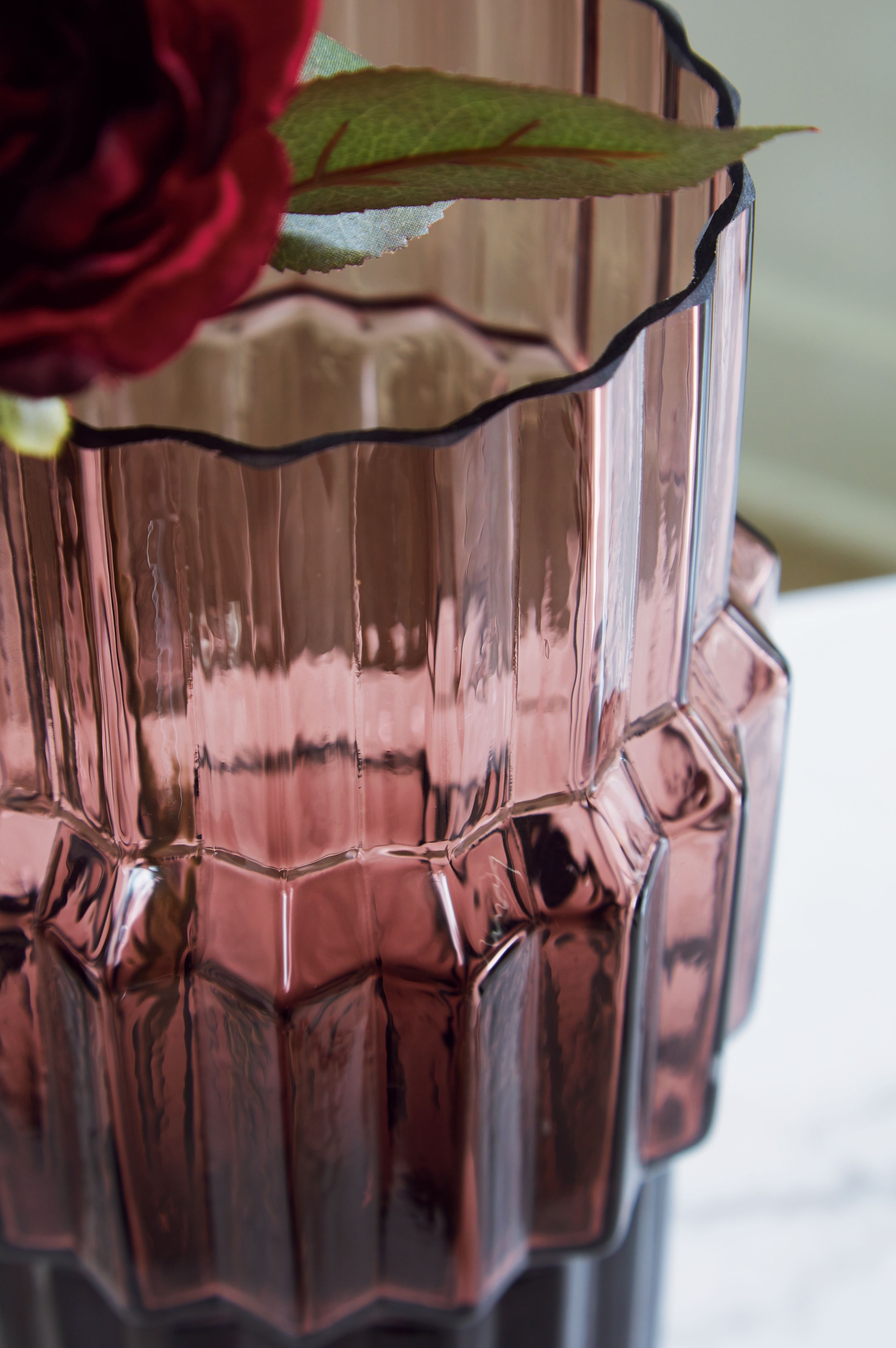 Purple faceted glass vase with fluted design and reflective vertical grooves