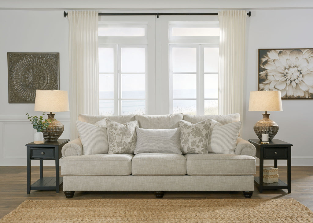 Light gray fabric loveseat sofa with patterned pillows and matching side table lamps