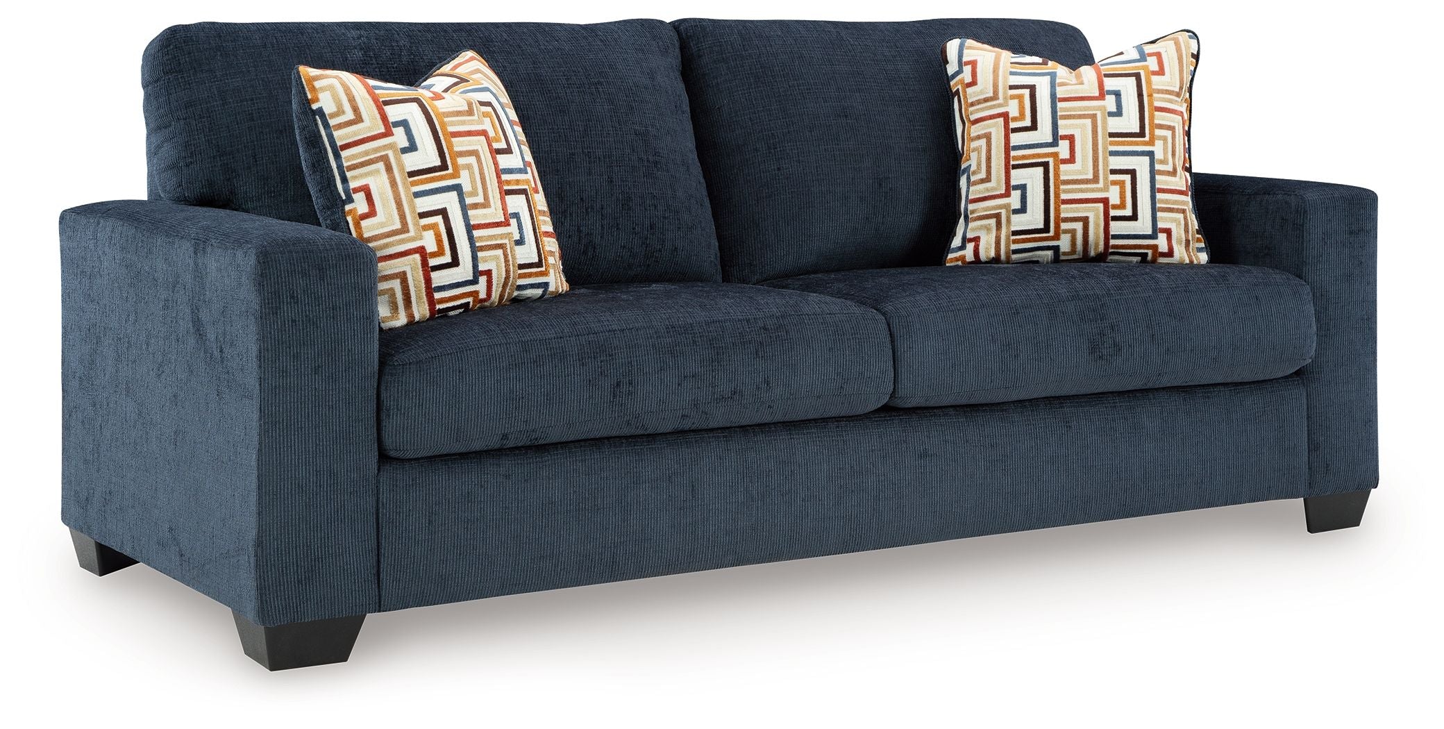 Ink blue sofa sleeper with two patterned throw pillows, front three-quarter view.
