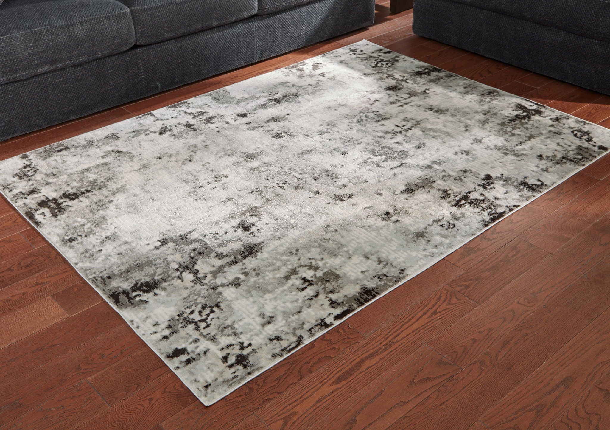 Abstract area rug with light-gray distressed design, viewed from the corner