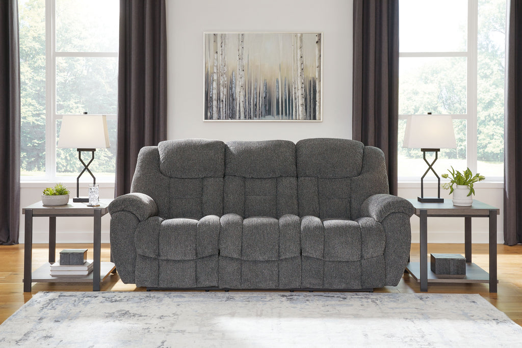 Charcoal gray reclining sofa with tufted back cushions and padded track arms