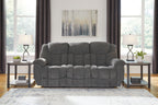 Charcoal gray reclining sofa with tufted back cushions and padded track arms