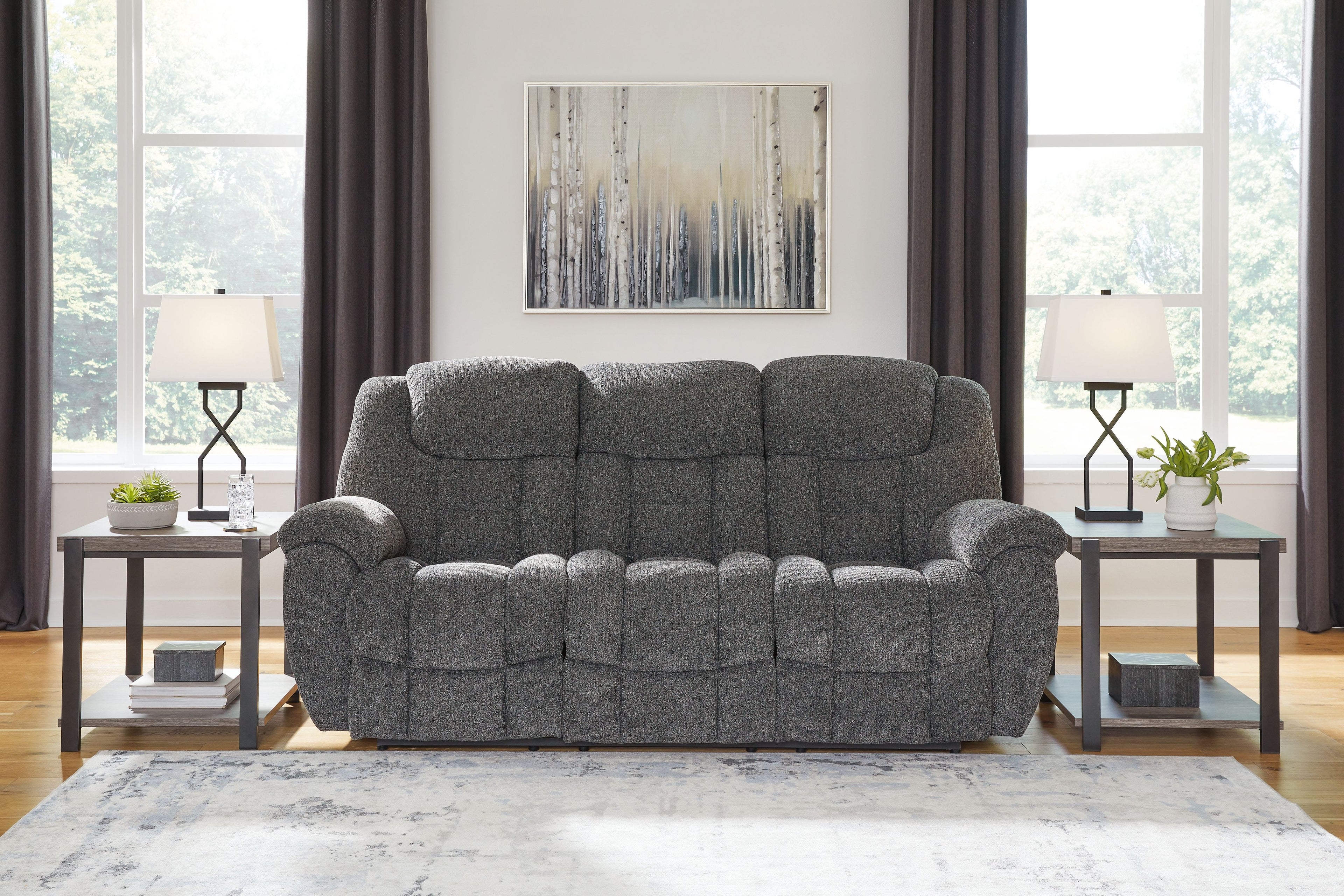 Charcoal gray reclining sofa with tufted back cushions and padded track arms