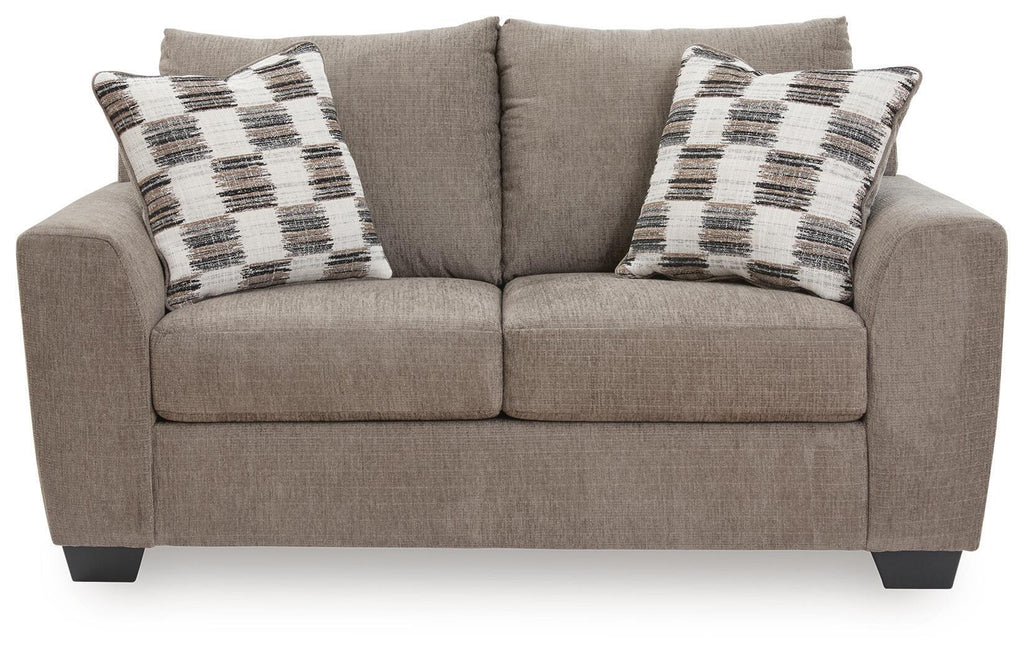 Light brown loveseat with two plaid throw pillows and centered back cushion
