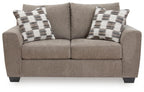 Light brown loveseat with two plaid throw pillows and centered back cushion